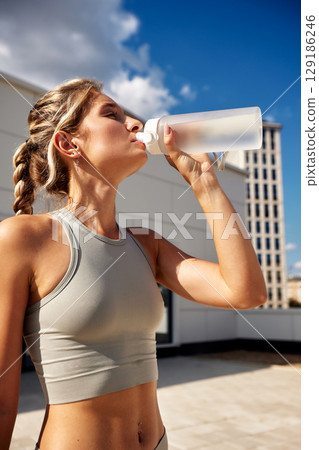 Active young woman drinking water outdoors during a sunny day workout Active young woman drinking water outdoors during a sunny day workout 129186246