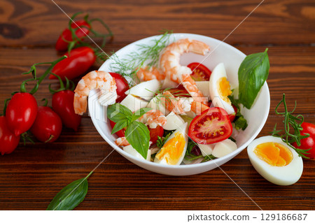 Salad with protein and greens on a wooden board 129186687