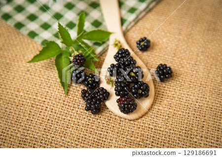 Black blackberries on wooden spoon in rustic style Black blackberries on wooden spoon in rustic style 129186691