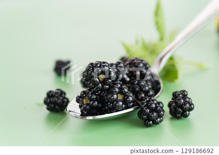 Black blackberries with greenery on a green background 129186692