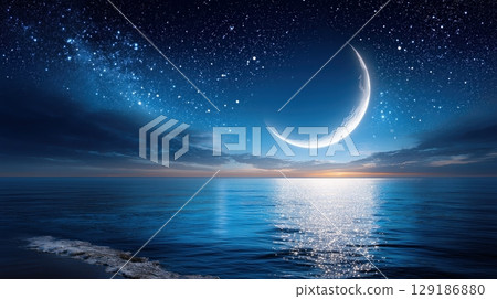 A bright crescent moon shines over a tranquil ocean with a starry sky and gentle waves on the shore 129186880