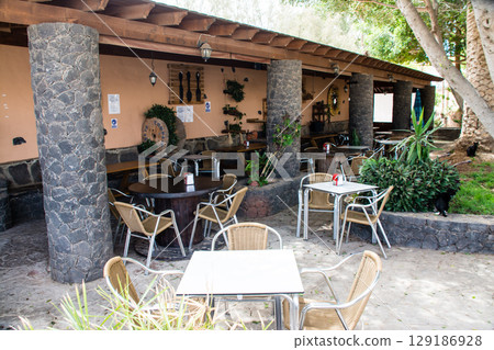A restaurant terrace with stone pillars and cobblestones under bright sunlight in the town of Betancuria on Fuerteventura A restaurant terrace with stone pillars and cobblestones under bright sunlight in the town of Betancuria on Fuerteventura 129186928
