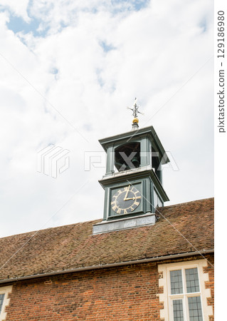 A clock tower on the red roof of a historic building under a clear sky in Osterley Park on the outskirts of London A clock tower on the red roof of a historic building under a clear sky in Osterley Park on the outskirts of London 129186980