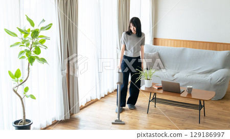 A woman cleaning the living room with a vacuum cleaner A woman cleaning the living room with a vacuum cleaner 129186997