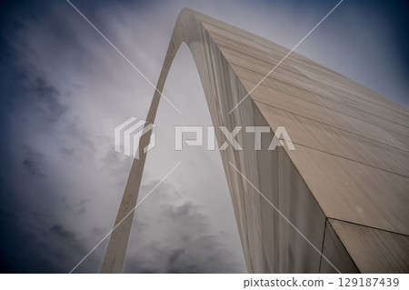 View from the base of the Gateway Arch National Park in St. Louis, Missouri showing the curve of metal against a blank sky 129187439