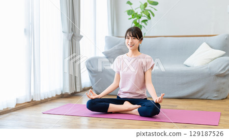 一位女士正在家中的客廳做瑜伽 129187526
