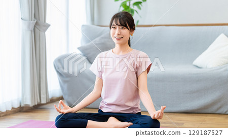 一位女士正在家中的客廳做瑜伽 一位女士正在家中的客廳做瑜伽 129187527