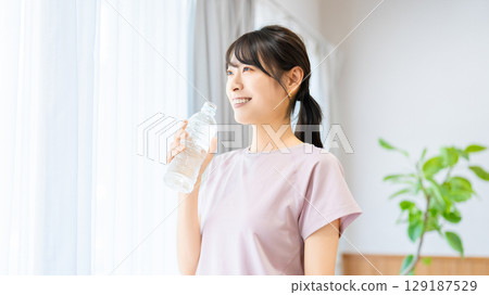 女人在窗邊喝瓶裝水 129187529