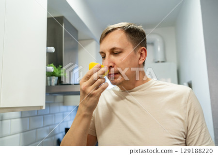 Man sniffing the lemon. Man sniffing the lemon. 129188220