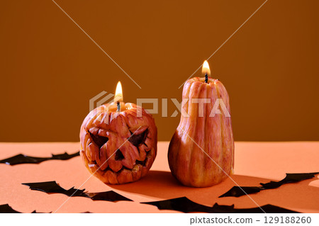 Halloween-style candles on a orange background. Festive decor. 129188260