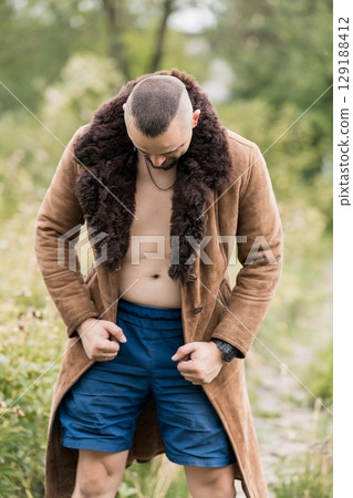 Rugged Man Outdoors: Brown Sheepskin Coat, Open Shirt, Blue Shorts, Forest Setting, Masculinity, Fall Style, Fashion, Autumnal Vibes. 129188412