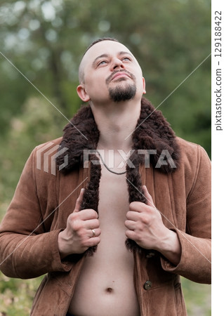 Man in Suede Jacket Outdoors, Looking Up, Brown Fur Collar, Natural Lighting, Forest Scene, Emotional Expression, Open Jacket, Rugged Style Man in Suede Jacket Outdoors, Looking Up, Brown Fur Collar, Natural Lighting, Forest Scene, Emotional Expression, Open Jacket, Rugged Style 129188422