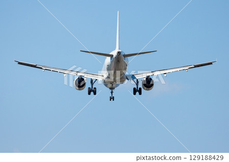 Passenger airplane in sky landing with aircraft landing gear, close up view 129188429
