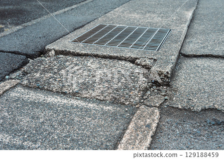 Dilapidated gutters and dangerous steps on the sidewalk 129188459