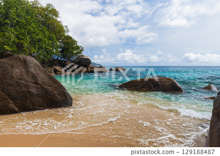 Serene Tropical Beach with Clear Waters and Large Natural Rock Formations Serene Tropical Beach with Clear Waters and Large Natural Rock Formations 129188487