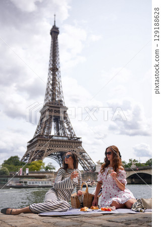 Women having picnic by Eiffel Tower in Paris France 129188628