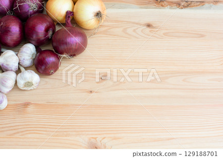 Red and yellow onions with garlic lie on a wooden background. copy space Red and yellow onions with garlic lie on a wooden background. copy space 129188701