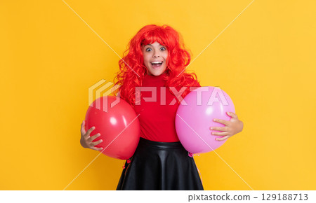 shocked teen child with party balloon on yellow background shocked teen child with party balloon on yellow background 129188713