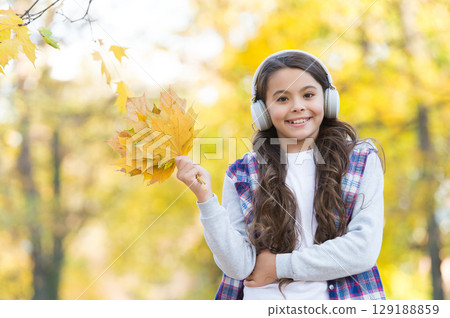 So beautiful. autumn kid fashion. inspiration. happy childhood. back to school. girl with maple leaves relax in park. fall beauty in forest. enjoy music in earphones. education online and e-learning So beautiful. autumn kid fashion. inspiration. happy childhood. back to school. girl with maple leaves relax in park. fall beauty in forest. enjoy music in earphones. education online and e-learning 129188859