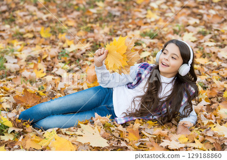 Perfect place to stay. child relax in autumn forest. fall maple leaves in park. childhood happiness. beauty and nature. happy kid wear headphones. teen girl listen music on the way to school 129188860