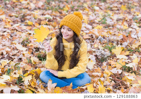 Playful mood. Warm woolen accessory. Girl long hair happy face fall nature background. Keep you warmest this autumn. Child in yellow hat outdoors. Hat keep warm. Kid wear warm soft knitted hat Playful mood. Warm woolen accessory. Girl long hair happy face fall nature background. Keep you warmest this autumn. Child in yellow hat outdoors. Hat keep warm. Kid wear warm soft knitted hat 129188863