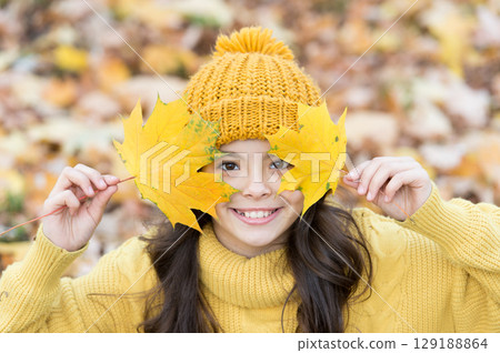 Cute smile of autumn. Happy girl play with yellow leaves. Little child smile on autumn day. Healthy and natural smile. Cosmetic dentistry. Feeling confident in her smile 129188864