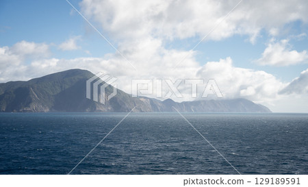 View on the mountainous coast from the boat sailing during cloudy day, New Zealand View on the mountainous coast from the boat sailing during cloudy day, New Zealand 129189591