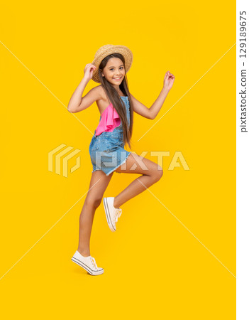 happy teen girl in straw hat running on yellow background happy teen girl in straw hat running on yellow background 129189675