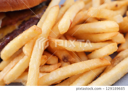 Crispy French Fries with a Juicy Cheeseburger in Background 129189685