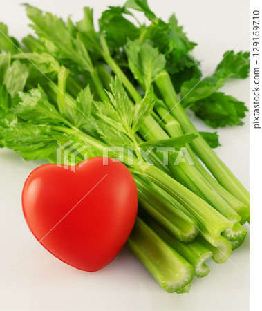 Healthy food concept. Green celery with red heart on white background. Vegetarian and vegan diet. Greens are good for heart health 129189710