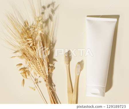 Organic oral care products set. Eco friendly composition with white tube of bio toothpaste, wooden toothbrushes bouquet of rye and wheat. Natural teeth hygiene concept. Mockup for natural toothpaste 129189723