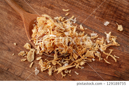 smoked onion flakes, on a wooden spoon, wooden table, close-up, smoked onion flakes, on a wooden spoon, wooden table, close-up, 129189735
