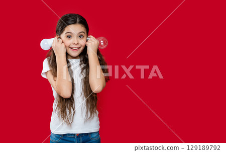 teen girl has solution isolated on red, copy space. teen girl has solution in studio. 129189792