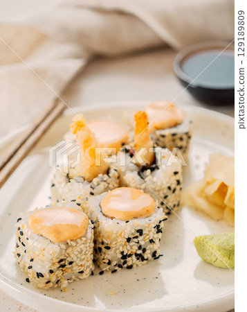 Tempura shrimp sushi roll - japanese food style on white plate over serving table. Shrimp tempura roll maki sushi Tempura shrimp sushi roll - japanese food style on white plate over serving table. Shrimp tempura roll maki sushi 129189809