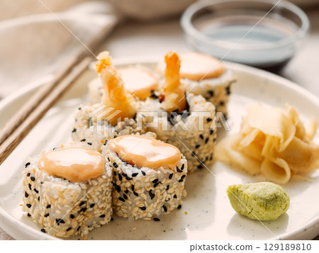 Tempura shrimp sushi roll - japanese food style on white plate over serving table. Shrimp tempura roll maki sushi Tempura shrimp sushi roll - japanese food style on white plate over serving table. Shrimp tempura roll maki sushi 129189810
