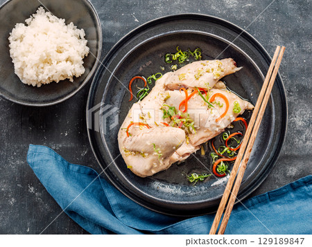 Sous Vide Chicken with spices. Boiled chicken sous-vide on black plate served with boiled rice. Sous-vide is culinary method of long-term cooking. Top view. 129189847