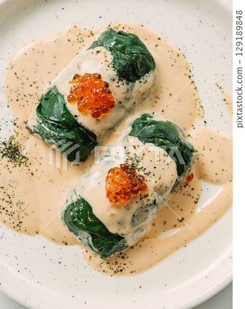 Stuffed green cabbage rolls with sauce in restaurant-style plating, served red caviar Stuffed green cabbage rolls with sauce in restaurant-style plating, served red caviar 129189848