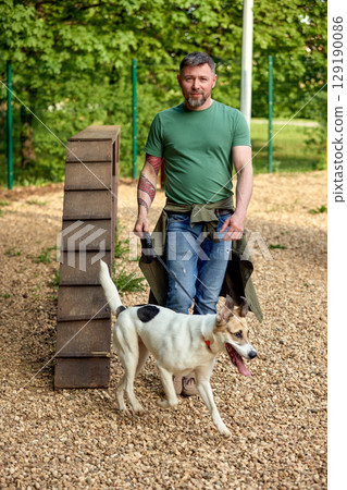 Man Walking His Dog in a Park With an Obstacle Course 129190086