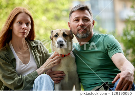 Couple enjoying time outdoors with their dog on a sunny day 129190090