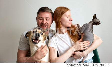 Couple enjoying the companionship of their dog and a sphynx cat Couple enjoying the companionship of their dog and a sphynx cat 129190103