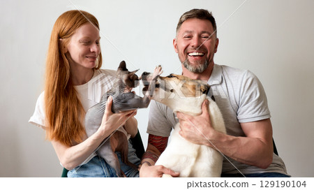 Happy couple with their dog and cat enjoying playful moments together Happy couple with their dog and cat enjoying playful moments together 129190104
