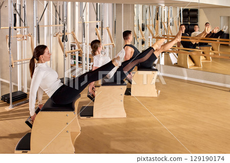 Group pilates training on Wunda chairs in a mirrored fitness studio 129190174