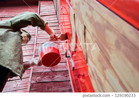 Painting process with flat paint brush conducted by house painter on metal entrance door of country house, action captured from low angle view. Painting process with flat paint brush conducted by house painter on metal entrance door of country house, action captured from low angle view. 129190233