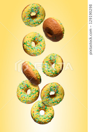 Yellow glazed donuts, each decorated with multi colored sprinkles. 129190298