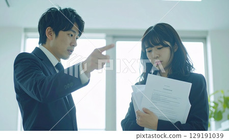 A female employee being scolded at work and a male employee pointing at her 129191039