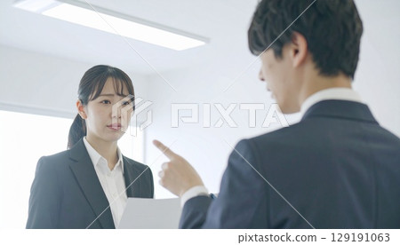 A female employee being scolded at work and a male employee pointing at her 129191063