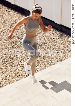 Woman exercising outdoors in sporty outfit while climbing steps on a sunny day Woman exercising outdoors in sporty outfit while climbing steps on a sunny day 129191094