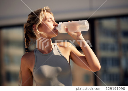 Athletic woman enjoying a refreshing drink during an outdoor workout session Athletic woman enjoying a refreshing drink during an outdoor workout session 129191098