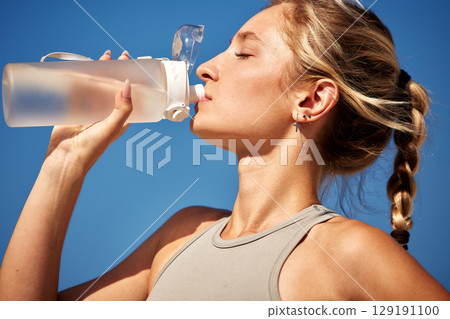 Young woman drinking water outdoors during a sunny day workout Young woman drinking water outdoors during a sunny day workout 129191100