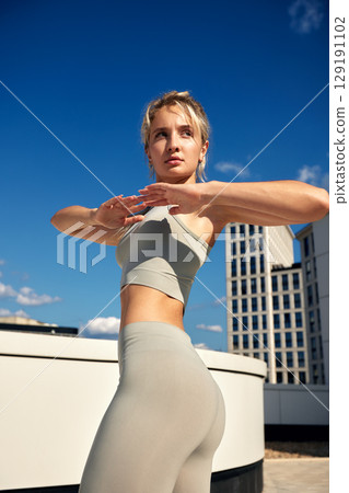 Young woman practicing outdoor fitness on a rooftop in athletic attire Young woman practicing outdoor fitness on a rooftop in athletic attire 129191102